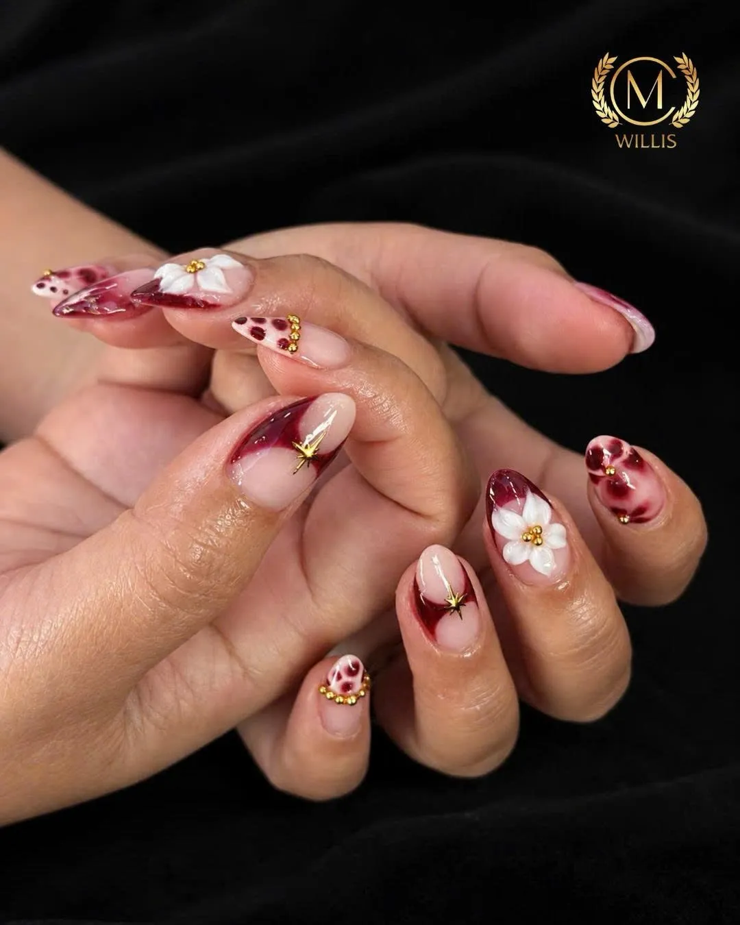 Almond nails with burgundy marble, white flowers and gold detailing