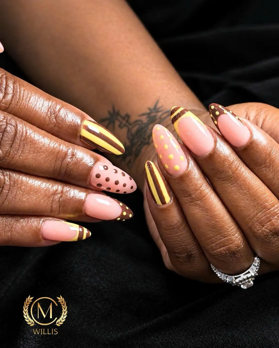 Nude almond nails with metallic gold stripes and black polka dots