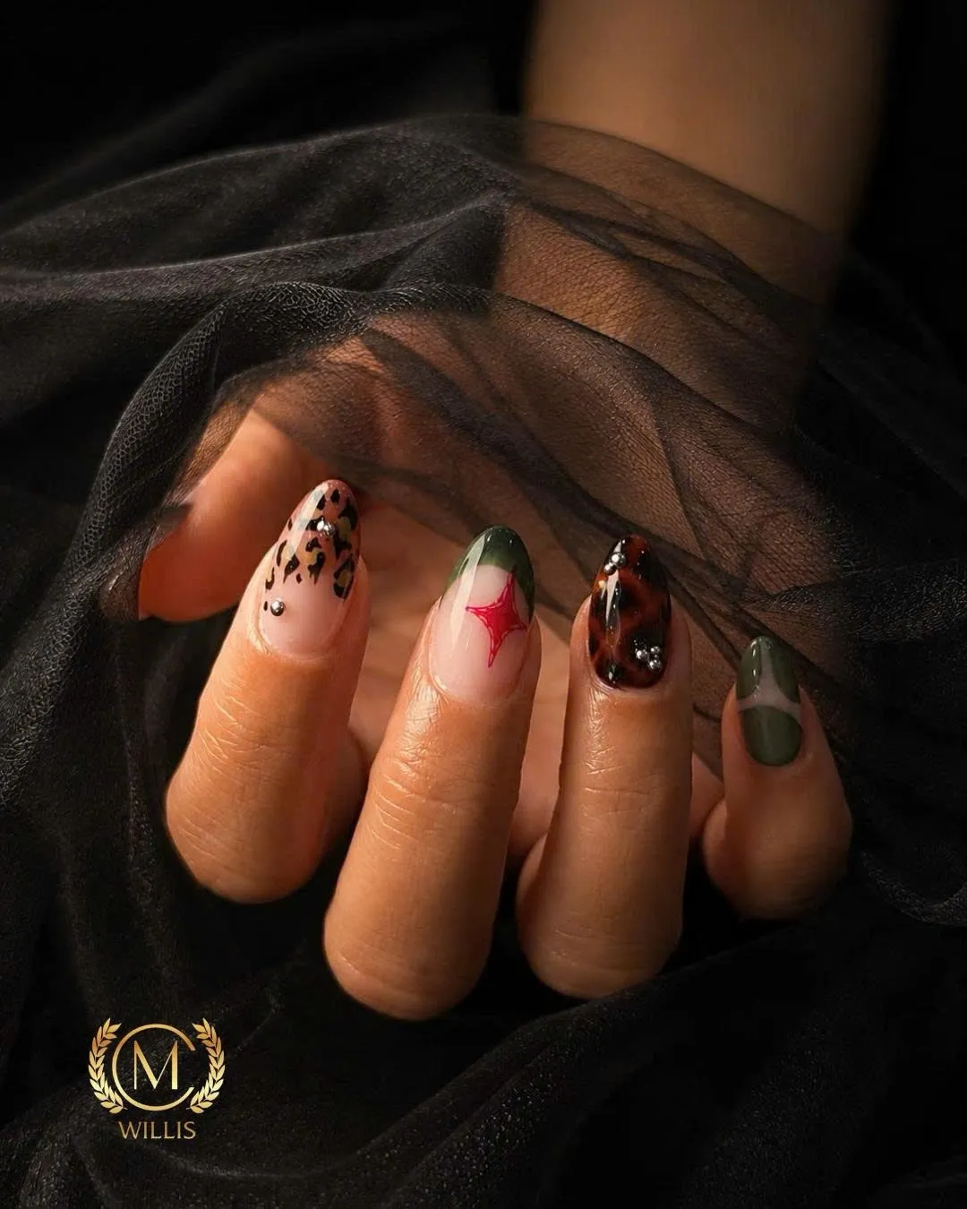 Almond nails under black tulle with leopard print, a red star, olive green and tortoiseshell