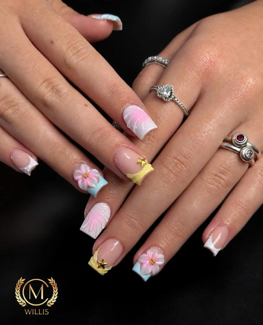 Short square nails with pastel French tips, 3D pink flowers, white swirls and gold stars
