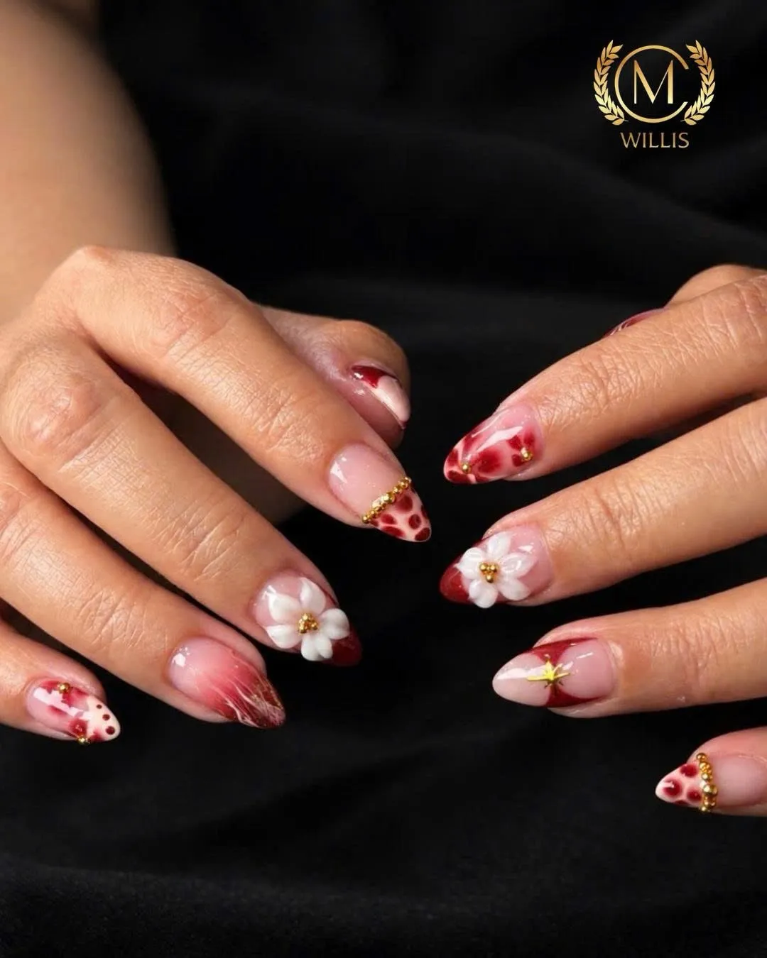 Short almond nails with red aura, a 3D white flower, cheetah dots and gold studs