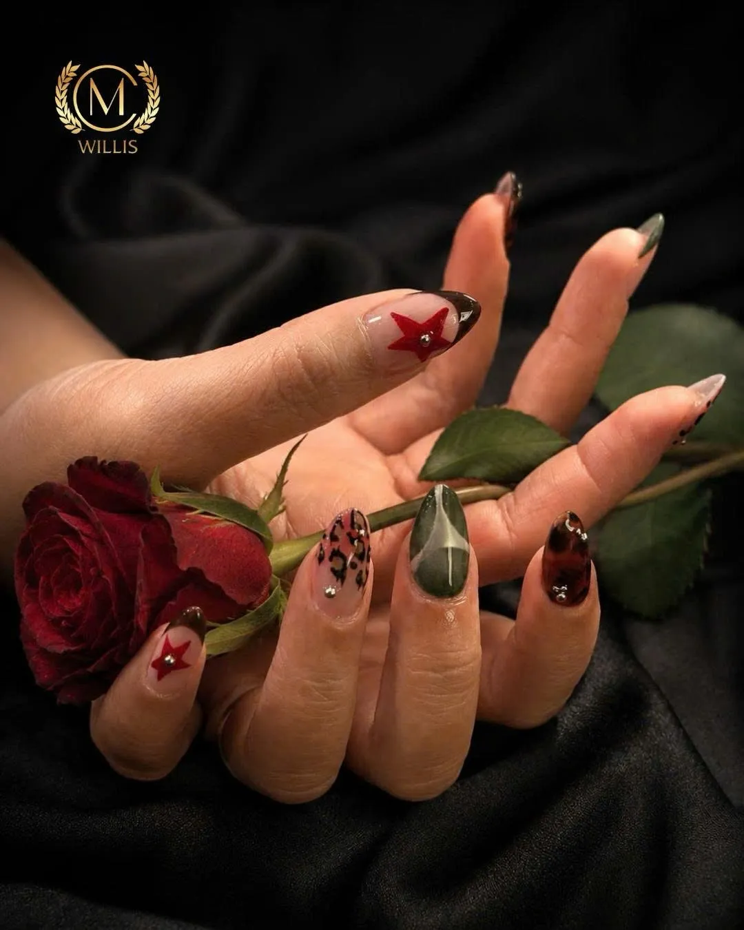 Short nails with red star accents and tortoiseshell details held beside a red rose